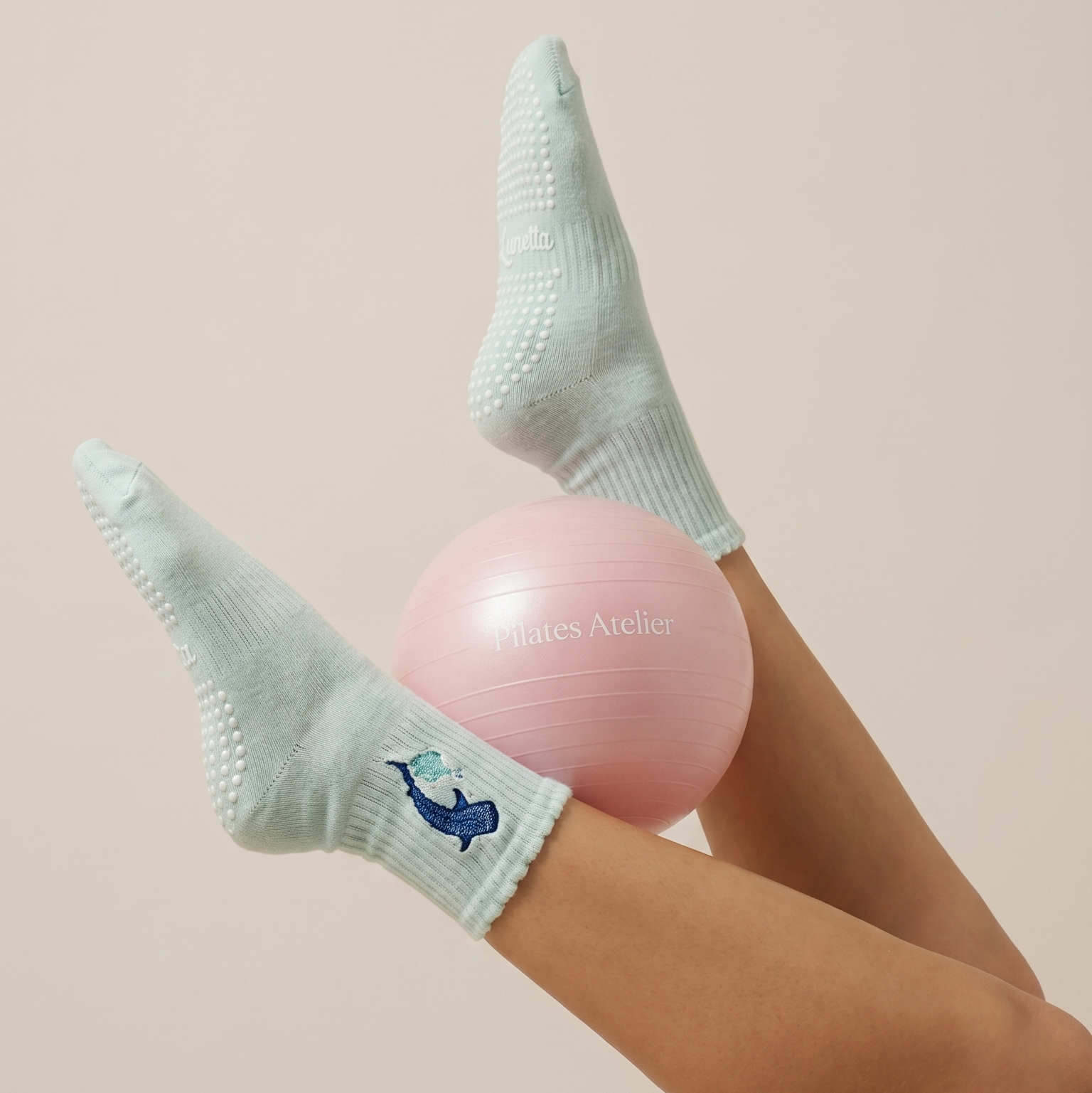 Light blue pilates socks with a featuring sea-inspired embroidery worn by a person holding a pilates ball