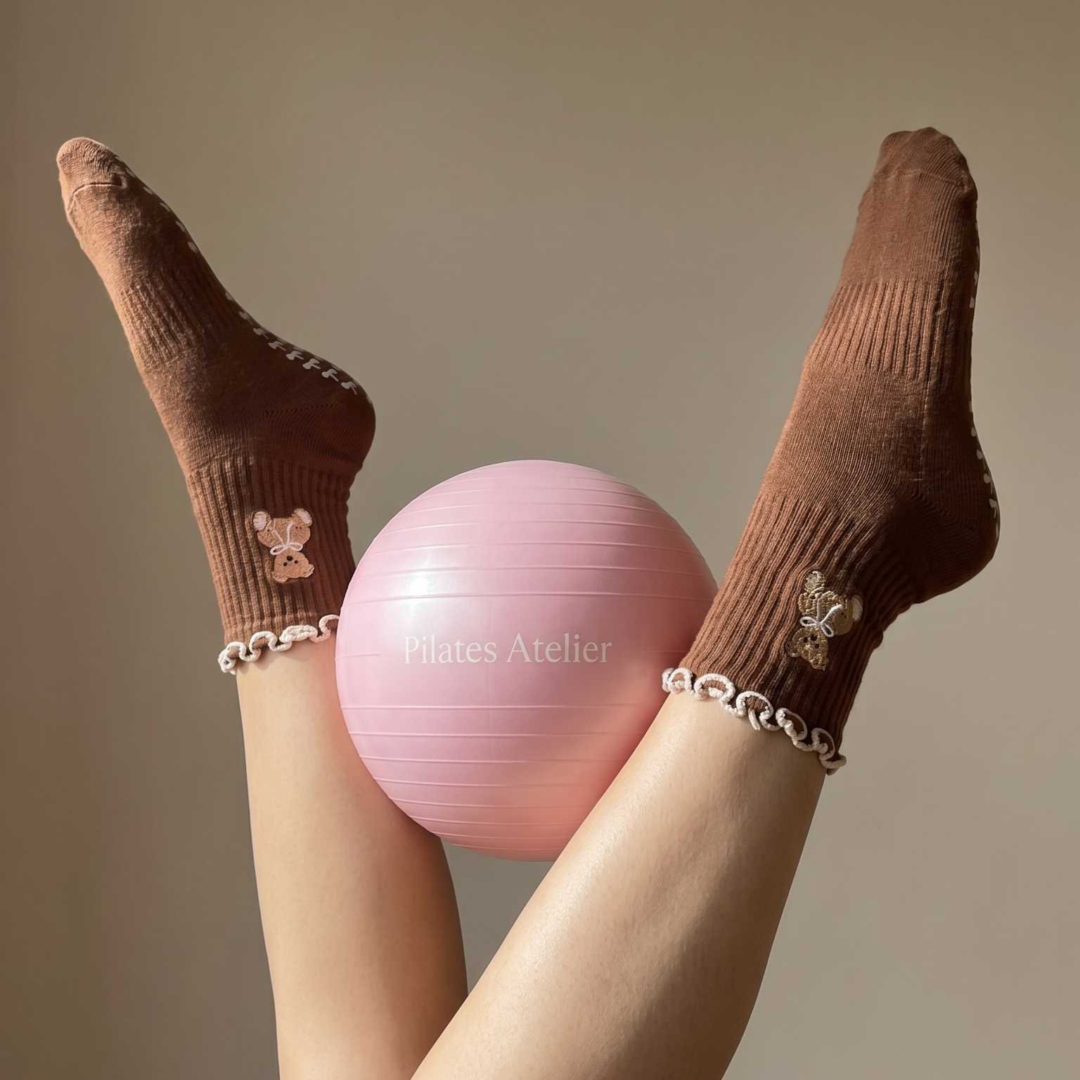 Pink exercise ball held by legs wearing cute brown Teddy Bear  pilates grip socks